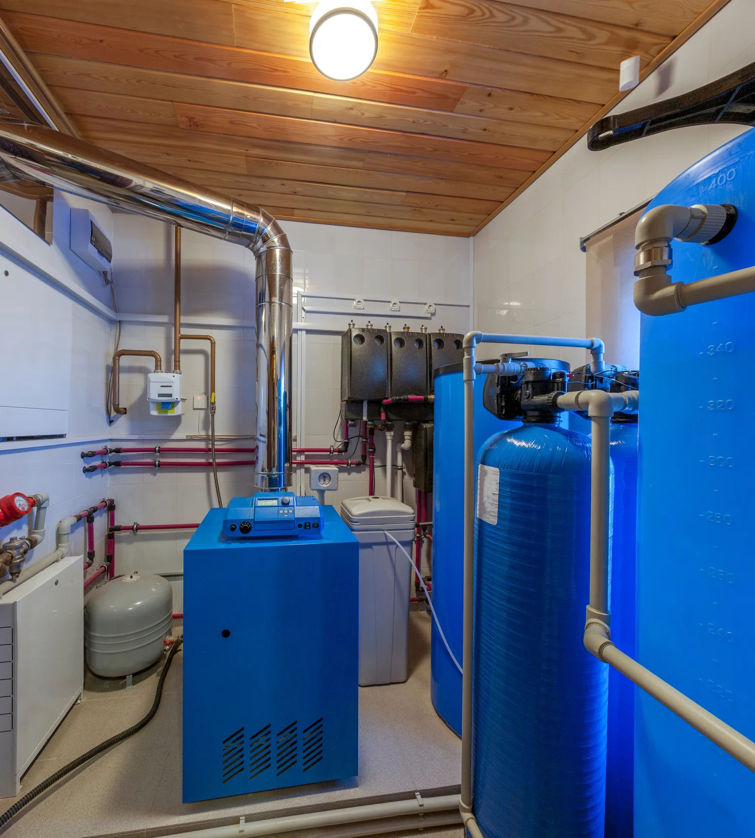 Interior view of a room with blue water tanks and pipes, associated with HVAC systems for furnace repair and replacement.