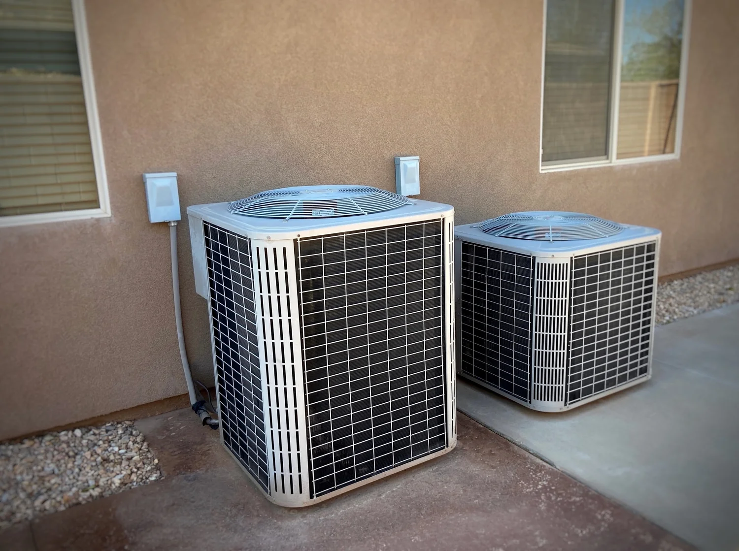 Two air conditioning units positioned outside a residential home, showcasing their installation for cooling purposes.