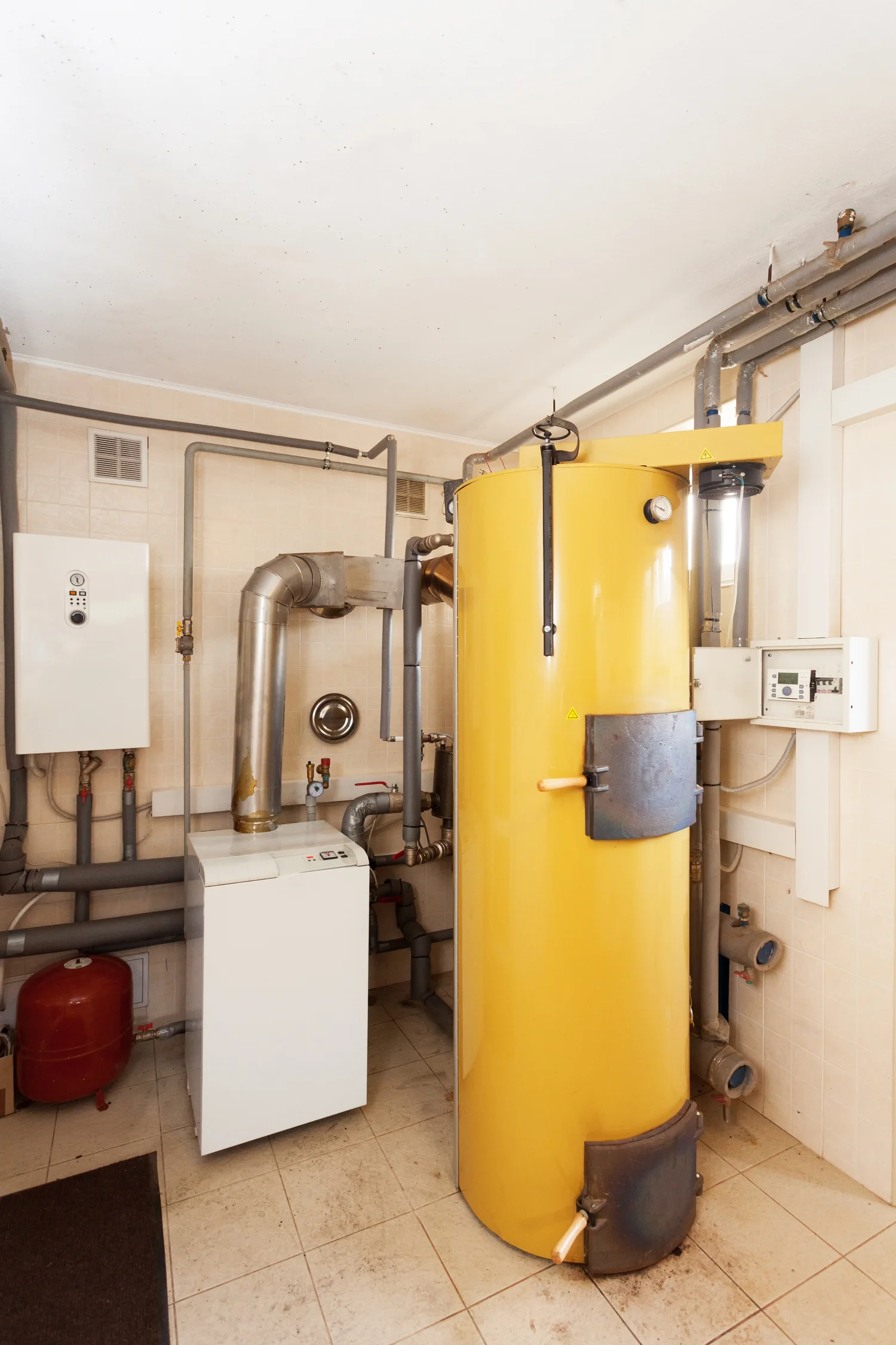 A yellow boiler surrounded by pipes and equipment in a room, illustrating HVAC installation and repair services.