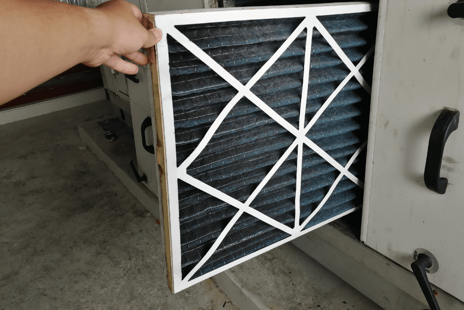 Technician checking and replacing a dirty HVAC air filter during routine maintenance